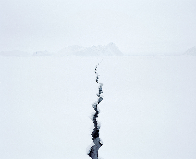 a fissure splits through the white field towards distant glaciers