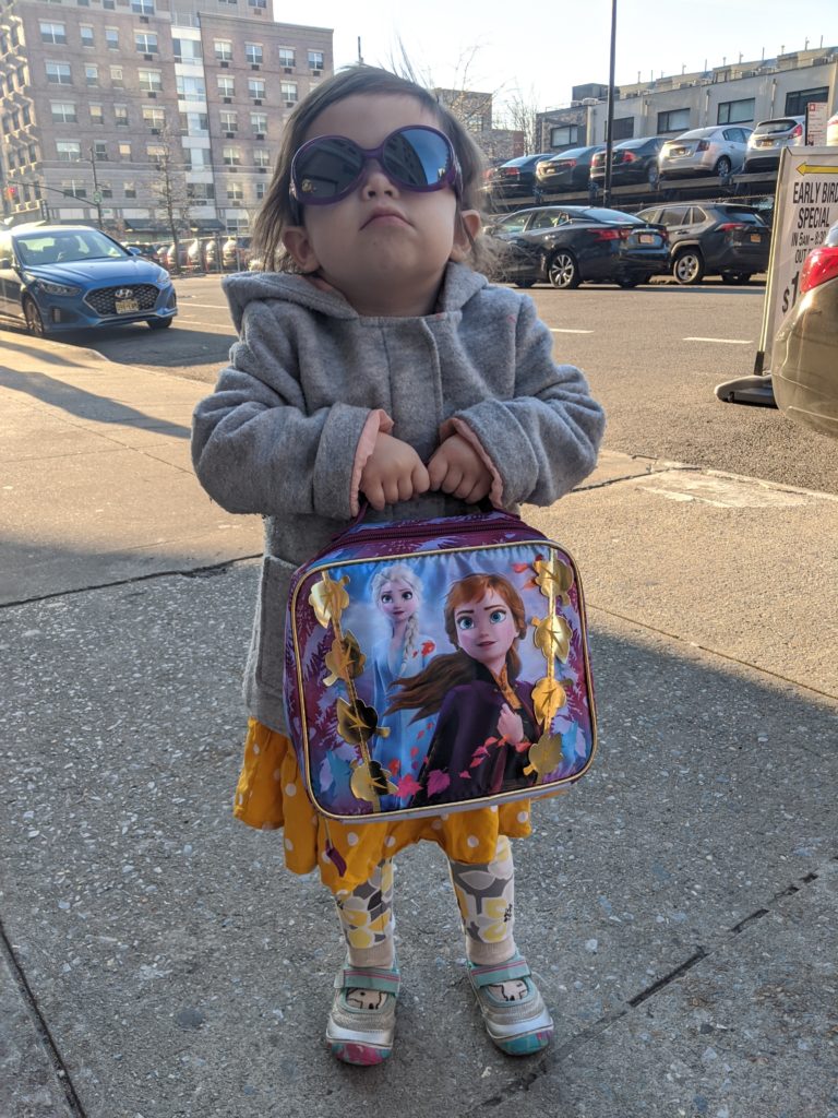 Zelda looking absolutely like a mean boss gripping her Frozen lunchbox and wearing oversized sunglasses