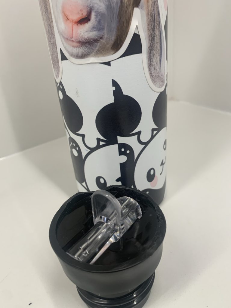 A water bottle covered in cute pandas and goat stickers. In front of it, the top is roughly rounded over and sanded down where it was damaged previously.